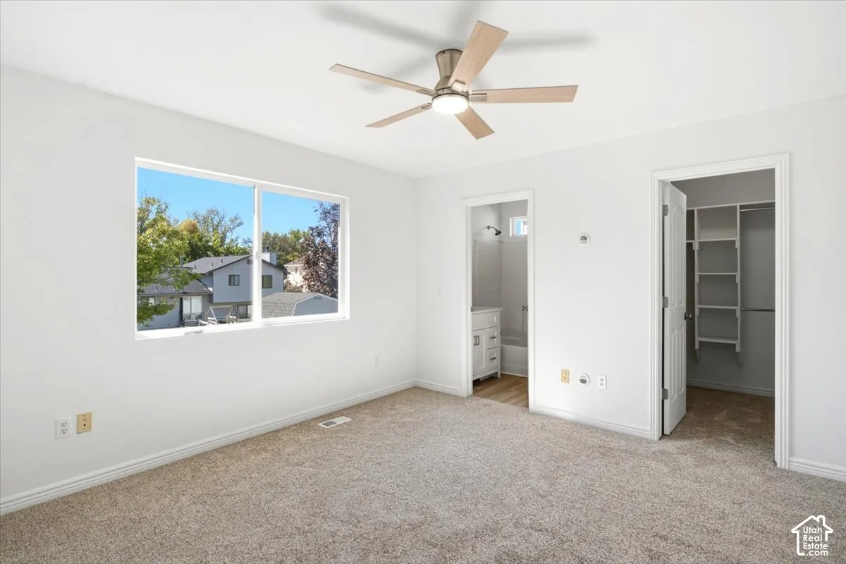 Master Bedroom featuring plush  carpet, large window, a ceiling fan with light, and access to a bathroom and closet with built-in shelving