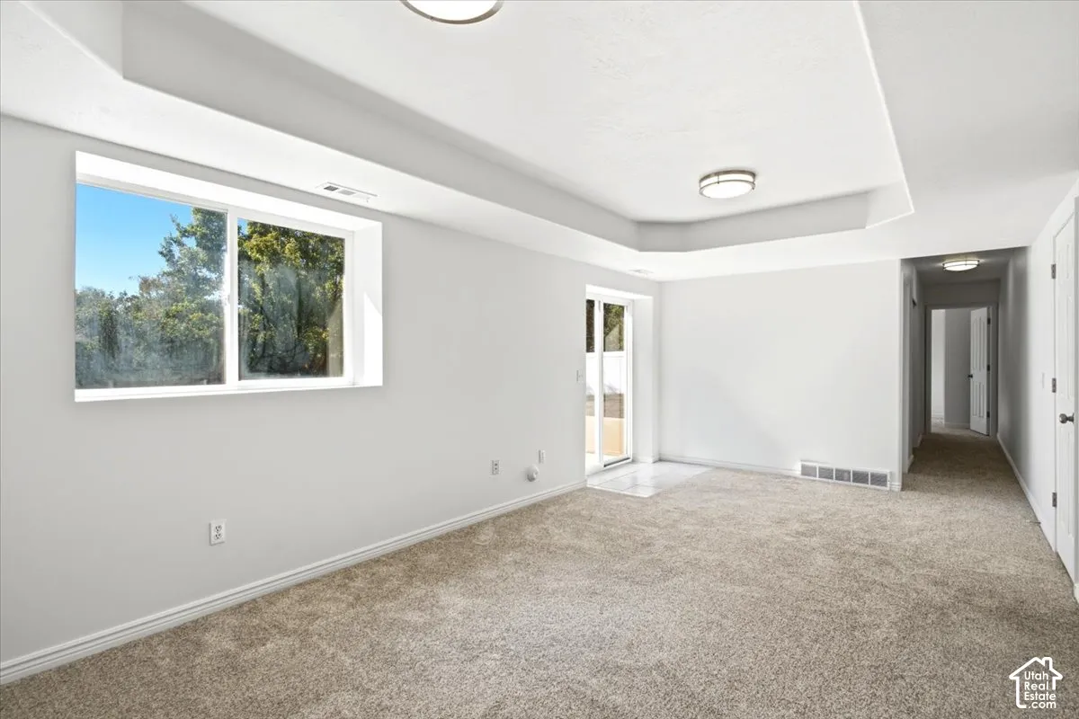 Recessed ceiling details, two flush-mount ceiling lights, light-toned carpeting, white walls, and a large window