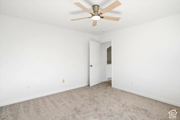 Master Bedroom Neutral tone wall color, plush carpet flooring, ceiling fan with integrated lighting, and a white paneled door