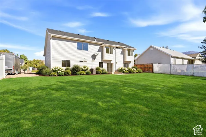 Potential look of backyard, expansive green lawn with mature landscaping, a private patio, and a light-colored siding exterior