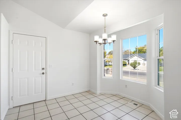 Tiled flooring with a grid pattern, multiple windows, a ceiling-mounted light fixture, and a paneled door