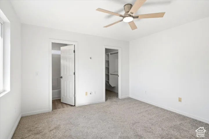 Master Bedroom with spacious bedroom with neutral carpeting, ceiling fan with brushed nickel finish, and multiple closet access points