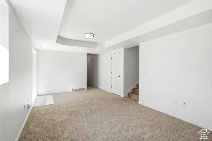 Carpeted flooring throughout, recessed ceiling detail, and a flush-mount ceiling light fixture
