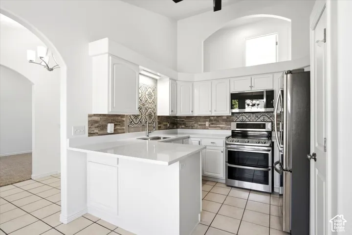 White cabinetry, stainless steel appliances, tile flooring, stone countertops, and decorative tile backsplash