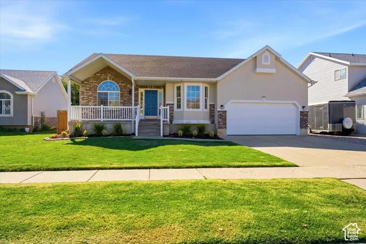 Exterior featuring a covered porch, white railing, arched window, and a two-car garage