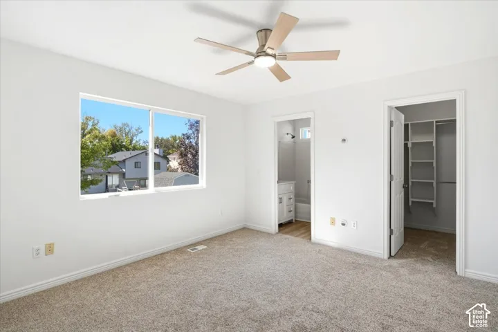 Master Bedroom featuring plush  carpet, large window, a ceiling fan with light, and access to a bathroom and closet with built-in shelving