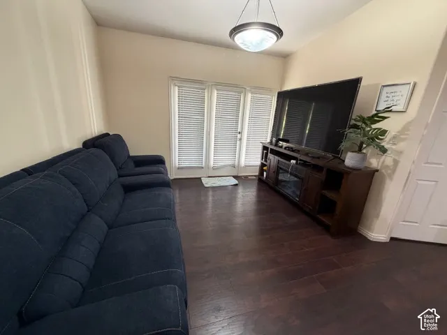 Vaulted ceiling, wood-finish flooring, white double doors with blinds, and a built-in media console