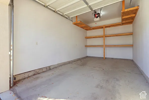 Garage featuring concrete flooring, an automated door opener, and built-in wooden shelving units