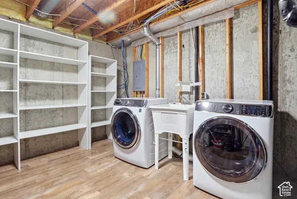 Utility area featuring built-in white shelving, a drop-in utility sink, and wood-finish flooring