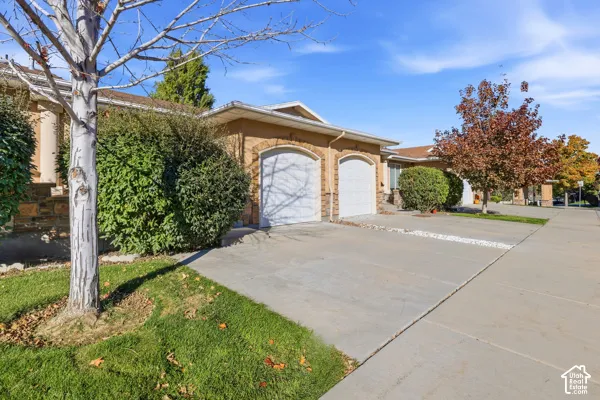 Exterior facade featuring stone veneer detailing, a double-car garage with arched entryways, and a concrete driveway