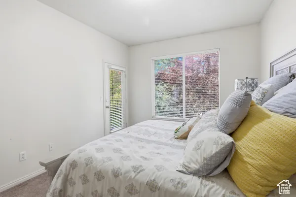 Room featuring neutral wall tones, wall-to-wall carpeting, a large sliding window, and a glass-paned door
