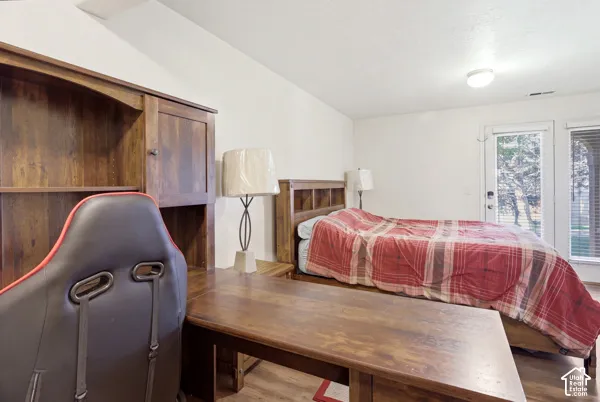 Vaulted ceiling, wood-finish flooring, and a glass-paneled exterior door