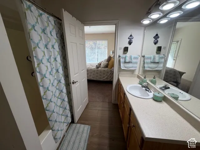 Full vanity with an integrated sink, track lighting, and wood-finish flooring
