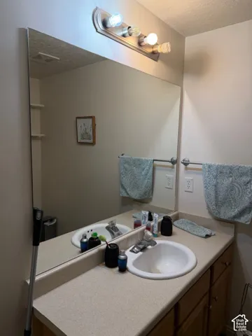 Double vanity with integrated sinks, expansive wall-mounted mirror, and wood-finish cabinetry