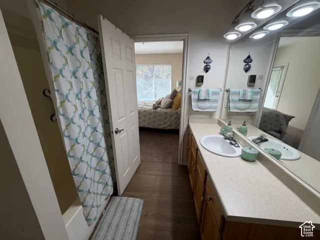 Bathroom featuring a single basin vanity with wood-finish cabinetry, a large mirror, and track lighting