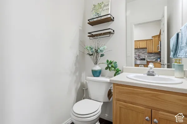 Restroom featuring a vanity with a solid-surface countertop, an integrated sink, and wood-finish cabinetry with silver-tone hardware