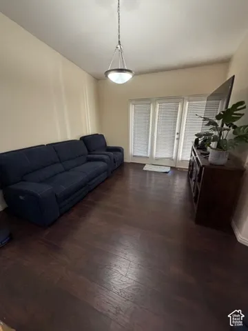 Wood-finish flooring, vaulted ceiling, suspended lighting fixture, and French doors with blinds