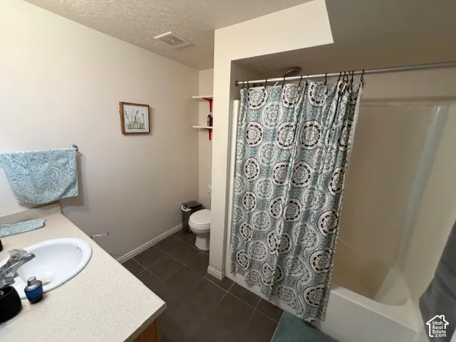 Built-in vanity with integrated sink, integrated tub/shower combination, and tiled flooring