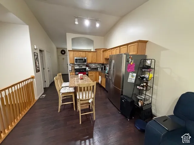 Spacious kitchen featuring wood cabinetry, stainless steel appliances, and ample counter space, opening to a dining area with wood-finish flooring throughout
