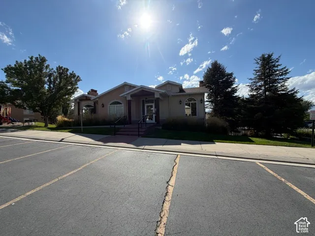 Stucco exterior with a covered entry, arched windows, and mature landscaping