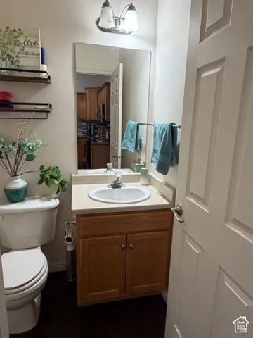 Powder room featuring a single vanity with wood-finish cabinetry, a white basin sink, and a wall-mounted mirror
