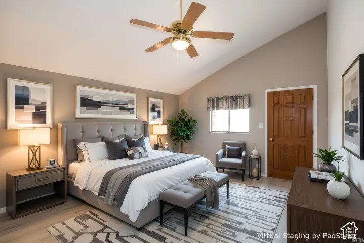 Vaulted ceiling with a ceiling fan, light wood-finish flooring, paneled wood door, and a window for natural illumination
