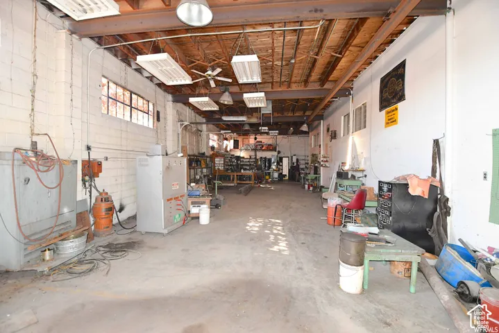 Spacious interior with exposed ceiling beams, industrial lighting fixtures, multiple window banks, and concrete flooring