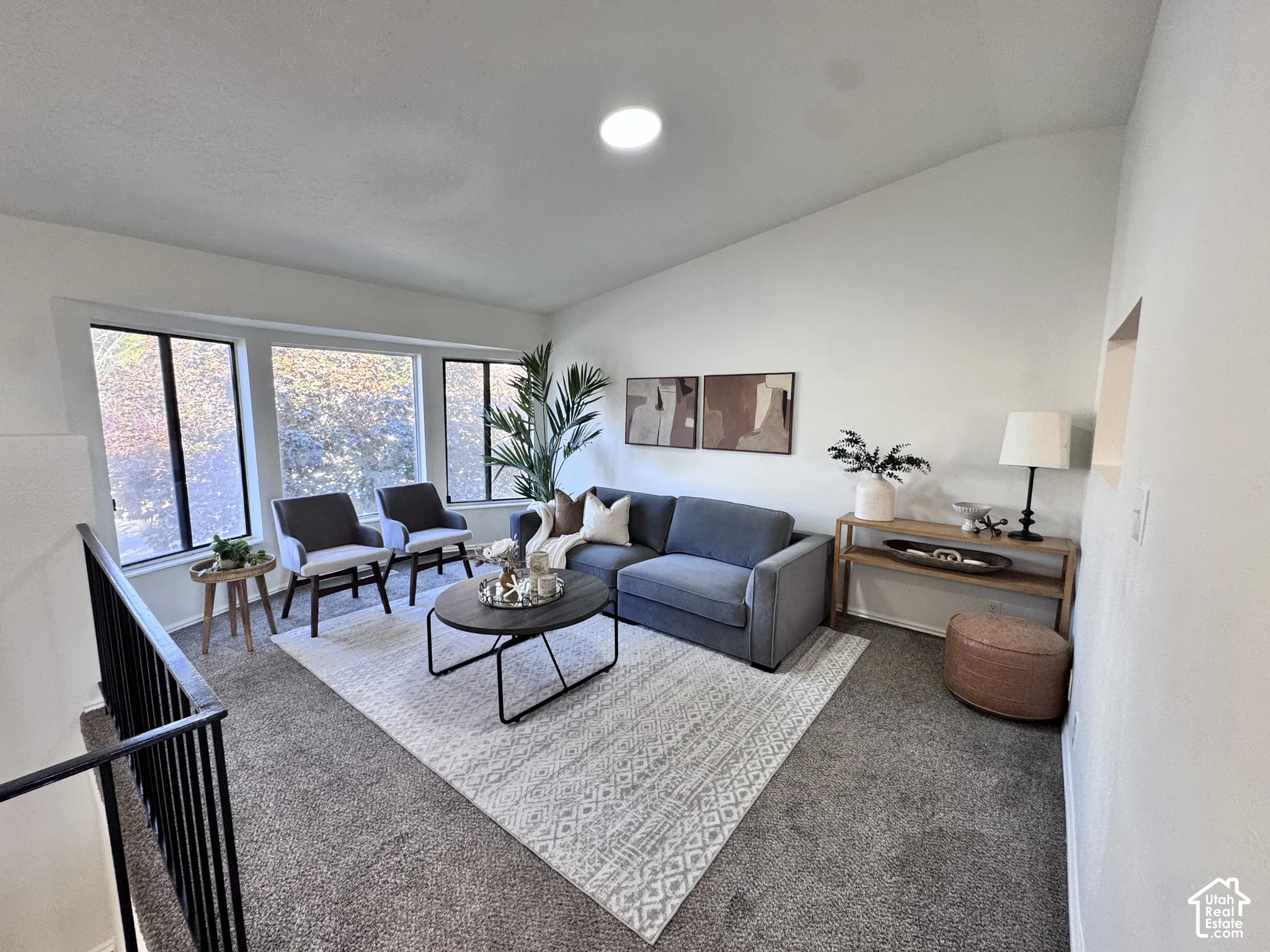 Vaulted ceiling with recessed lighting, bay window, and black metal railing