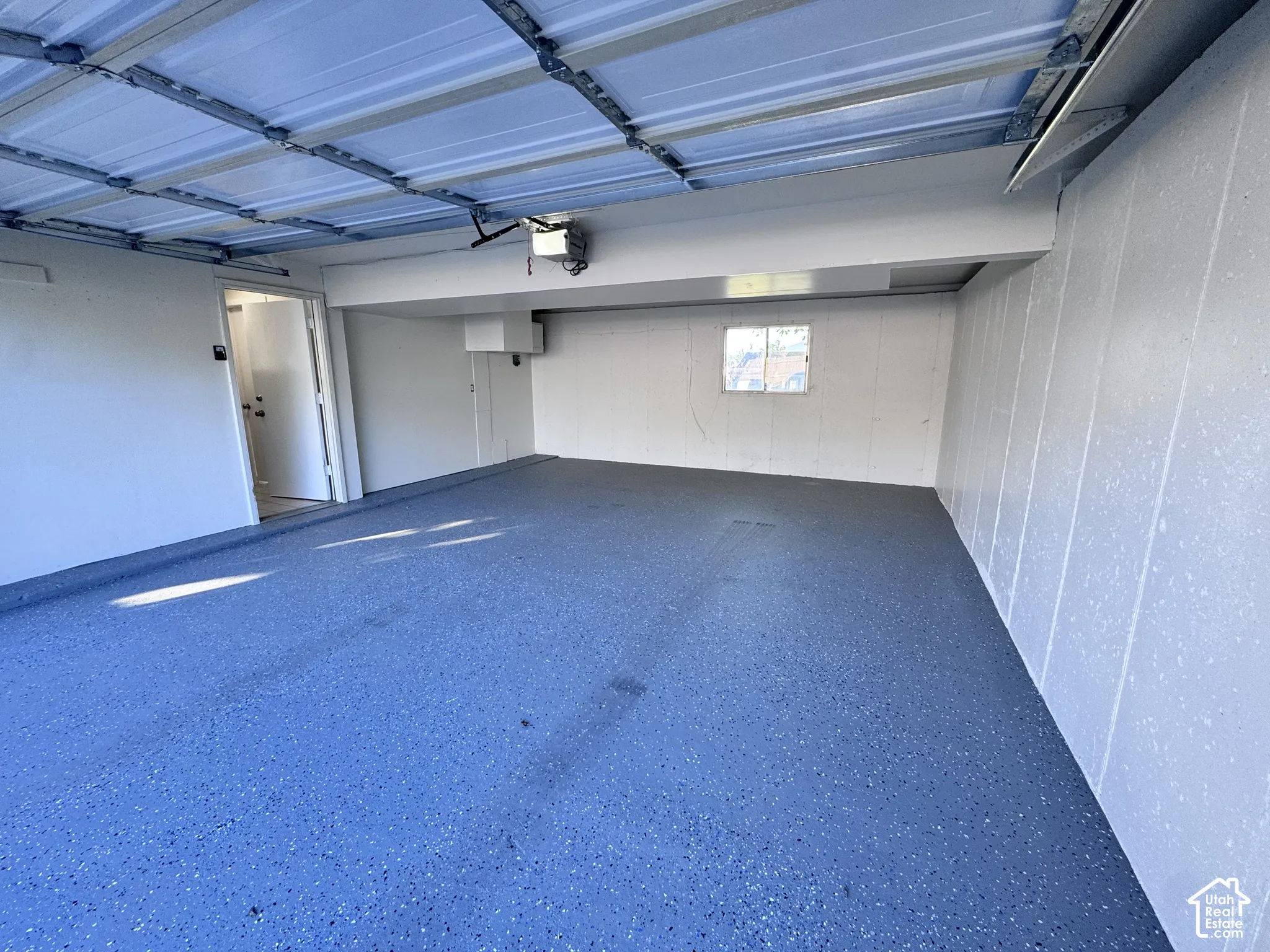 Spacious garage with an epoxy-coated flooring, insulated garage door, and a built-in window