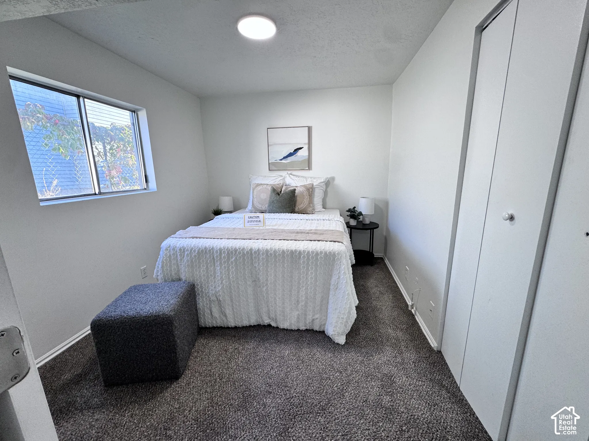 White walls with a single window, recessed overhead lighting, and carpeted flooring