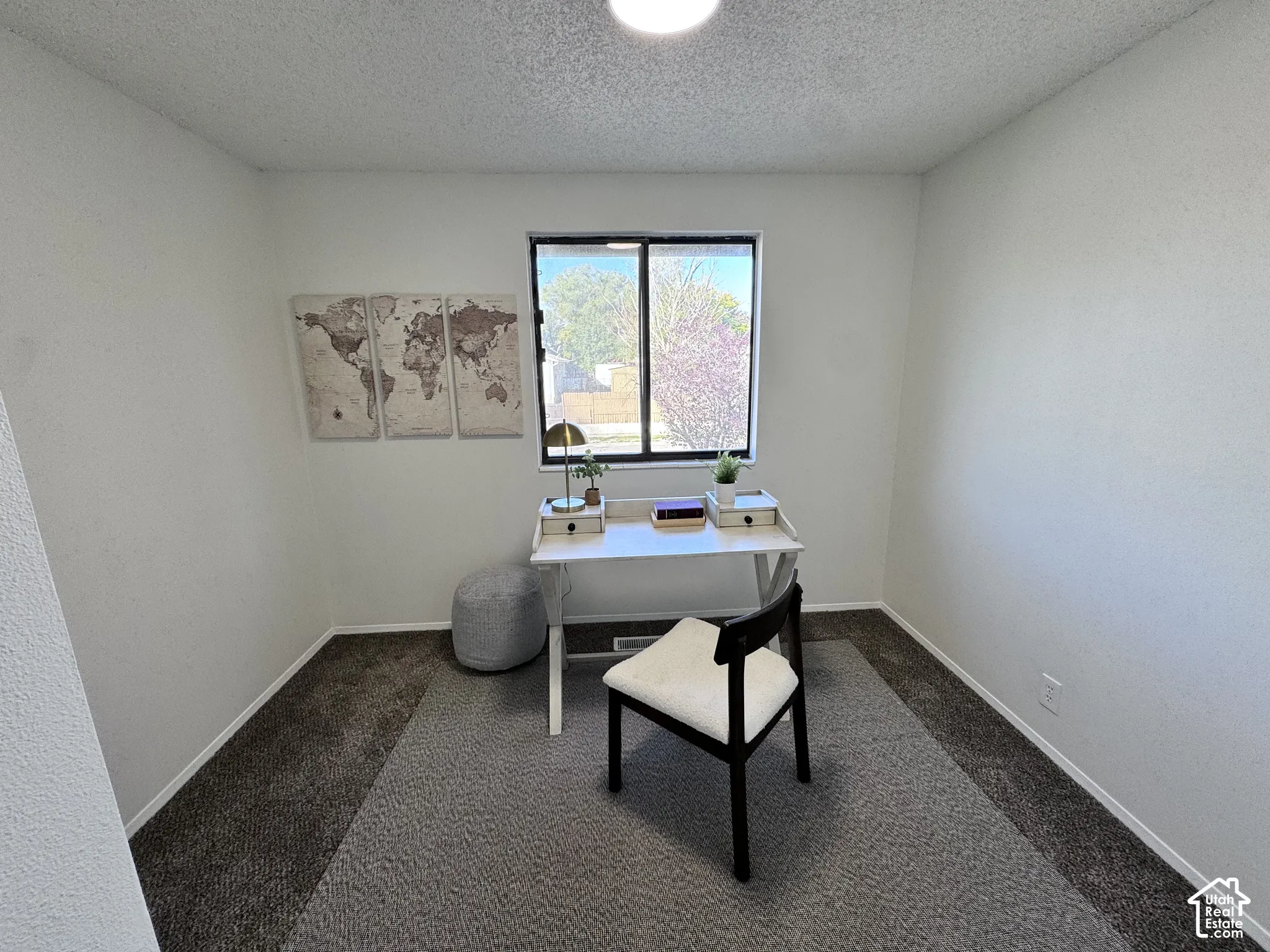White walls, dark carpet flooring, and a single-pane window