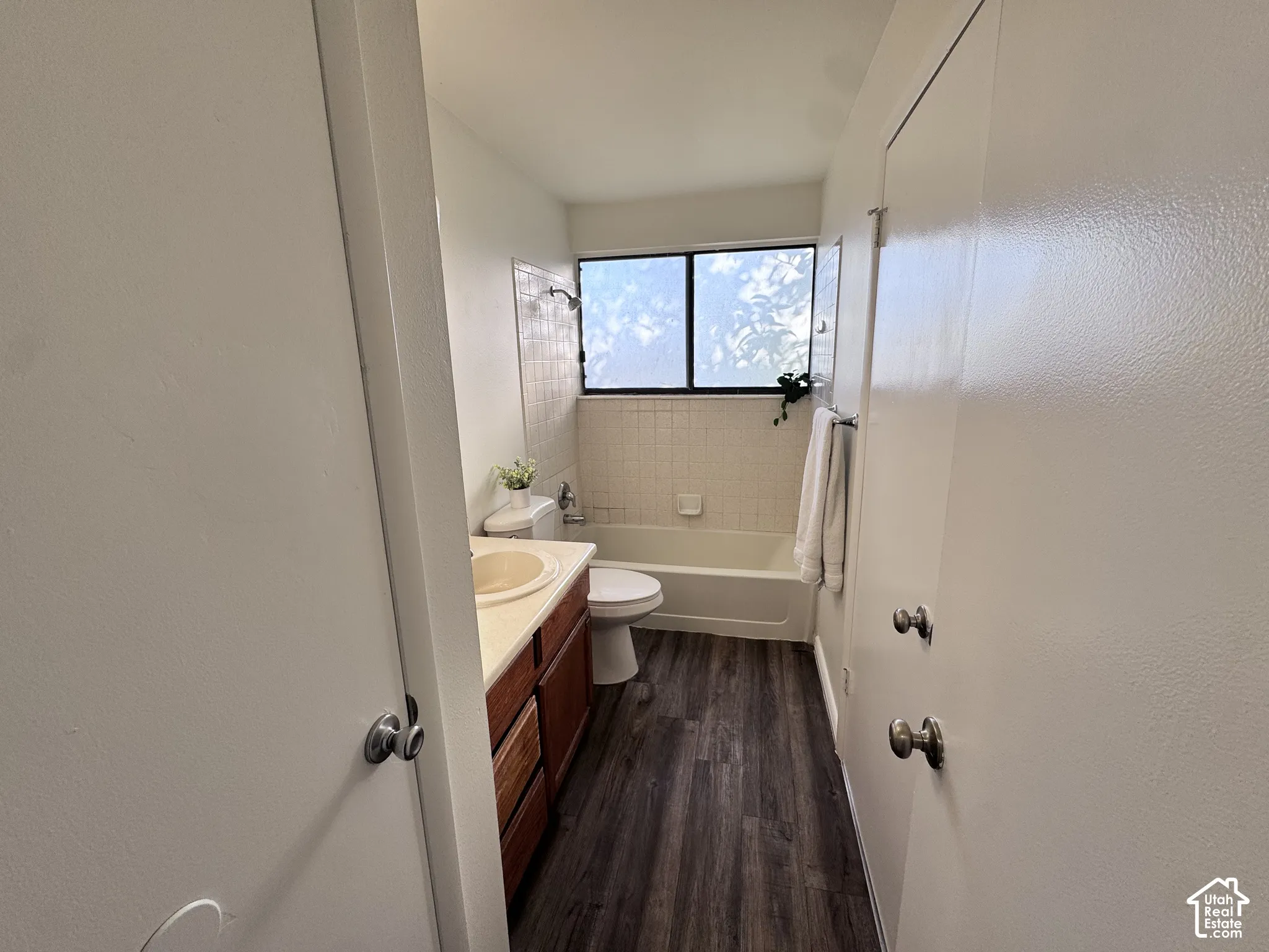 Full bathroom featuring a window, wood-finish flooring, a combination shower and tub, and a vanity with an integrated sink