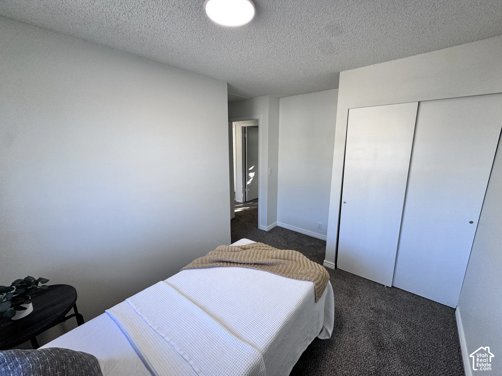 Recessed ceiling light, white walls, gray carpeting, and bi-fold closet doors