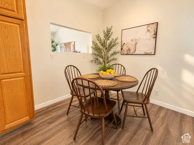 Wood-finish flooring with white baseboards, a built-in wood cabinet, and a wall cutout providing an opening to an additional space