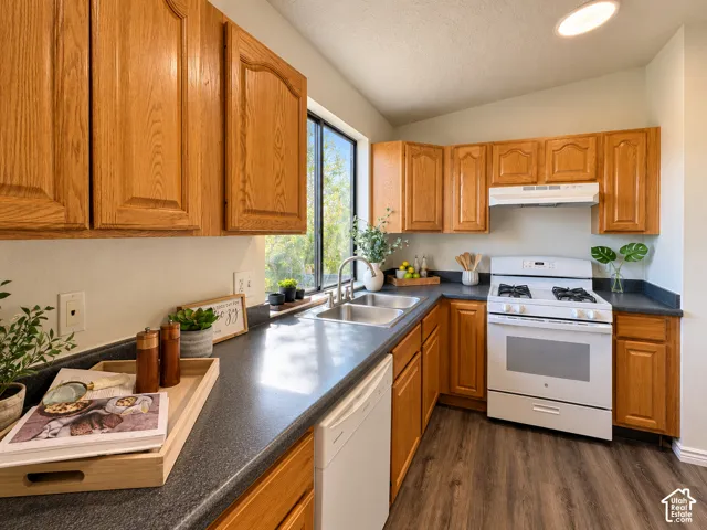 Kitchen featuring wood cabinetry, dark countertops, a window over the sink, wood-finish flooring, and a white range