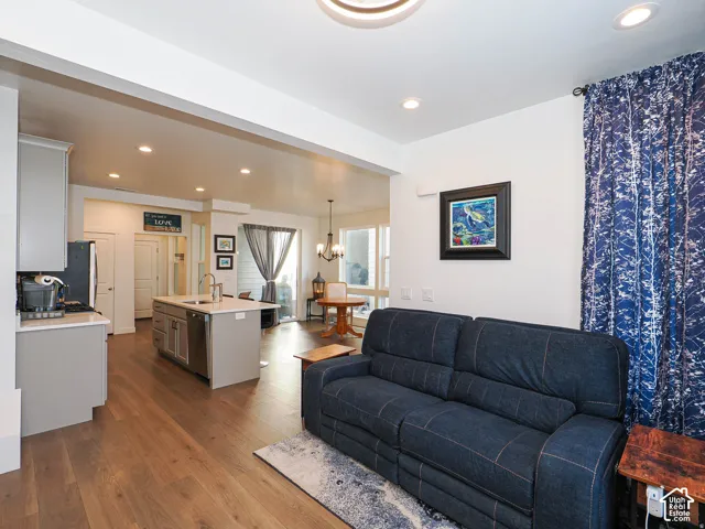 Open-concept living area with wood-finish flooring, recessed lighting, and a kitchen island with integrated sink
