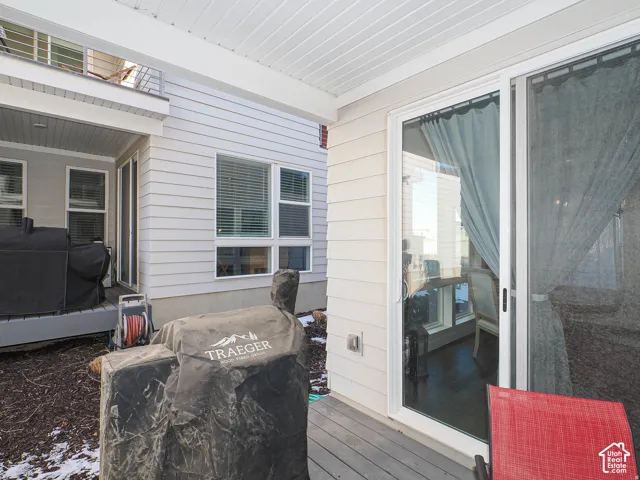 Covered patio with a sliding glass door, showcasing a deck and light-colored siding