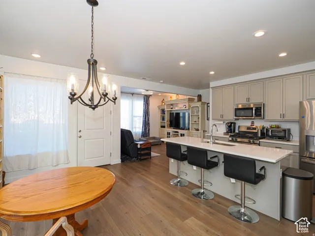 Open-concept kitchen and dining area featuring wood-finish flooring, recessed lighting, and a chandelier