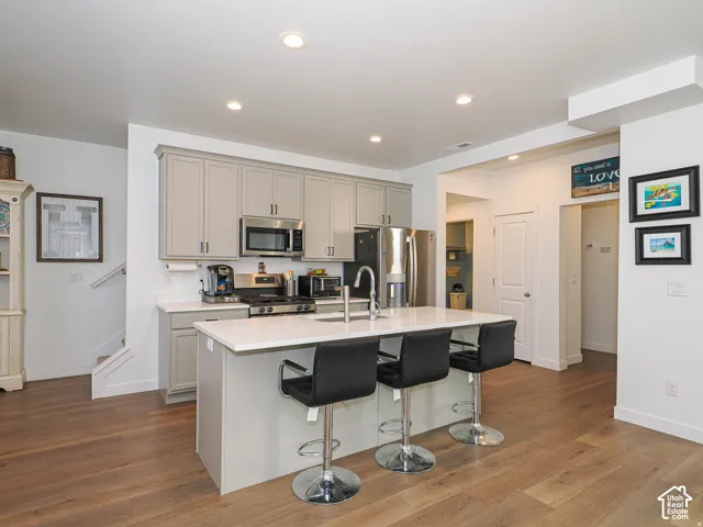 Kitchen featuring a central island, light-toned cabinetry, stainless steel appliances, and wood-finish flooring