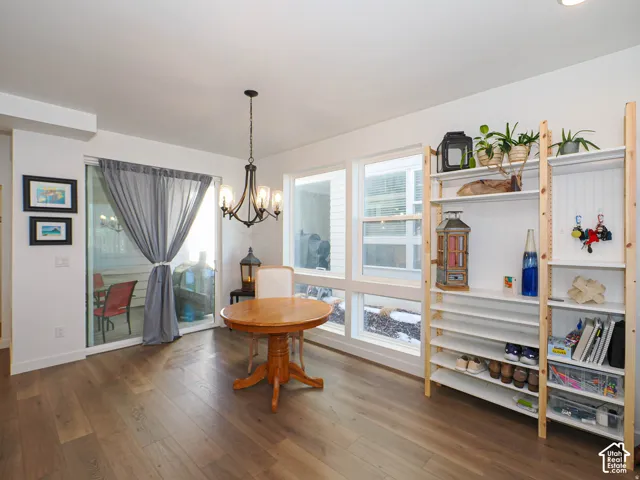 Light wood-finish flooring, a contemporary chandelier, multiple large windows, and a sliding glass door provide natural illumination