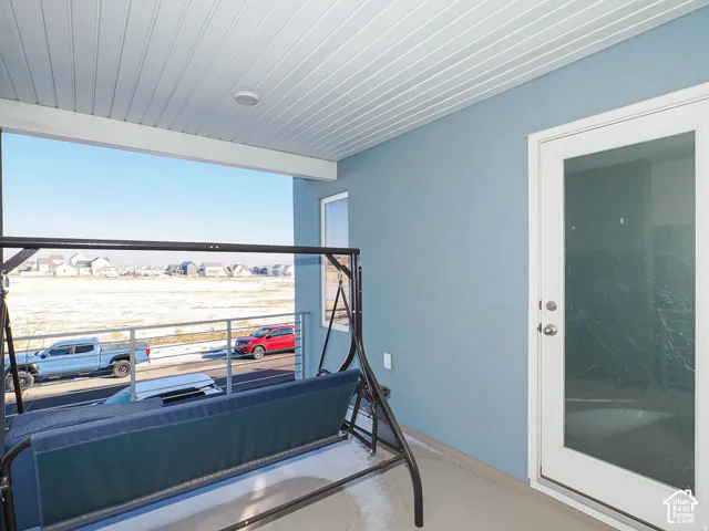 Recessed lighting, wood-finish ceiling, light blue exterior wall, white framed glass door, and a metal railing