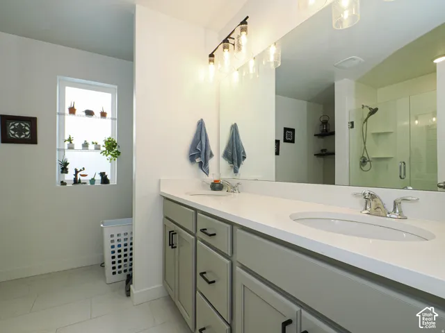 Dual vanity with integrated sinks, light-colored countertop, and gray cabinetry with black hardware