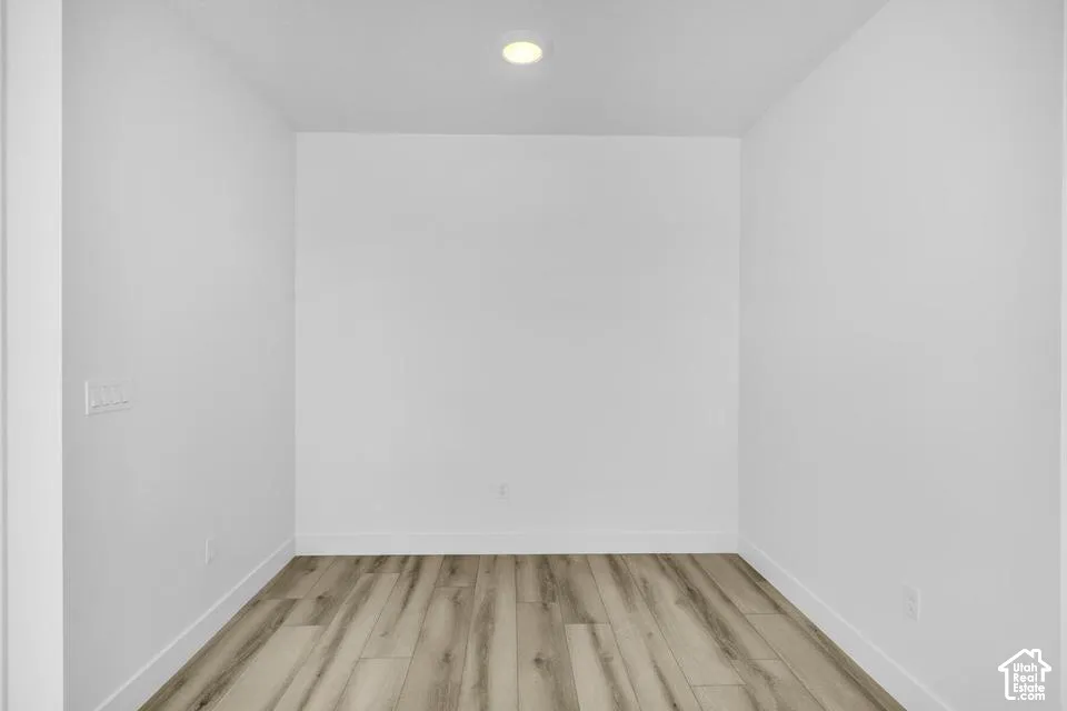 Wood-finish flooring, recessed ceiling light, and white walls