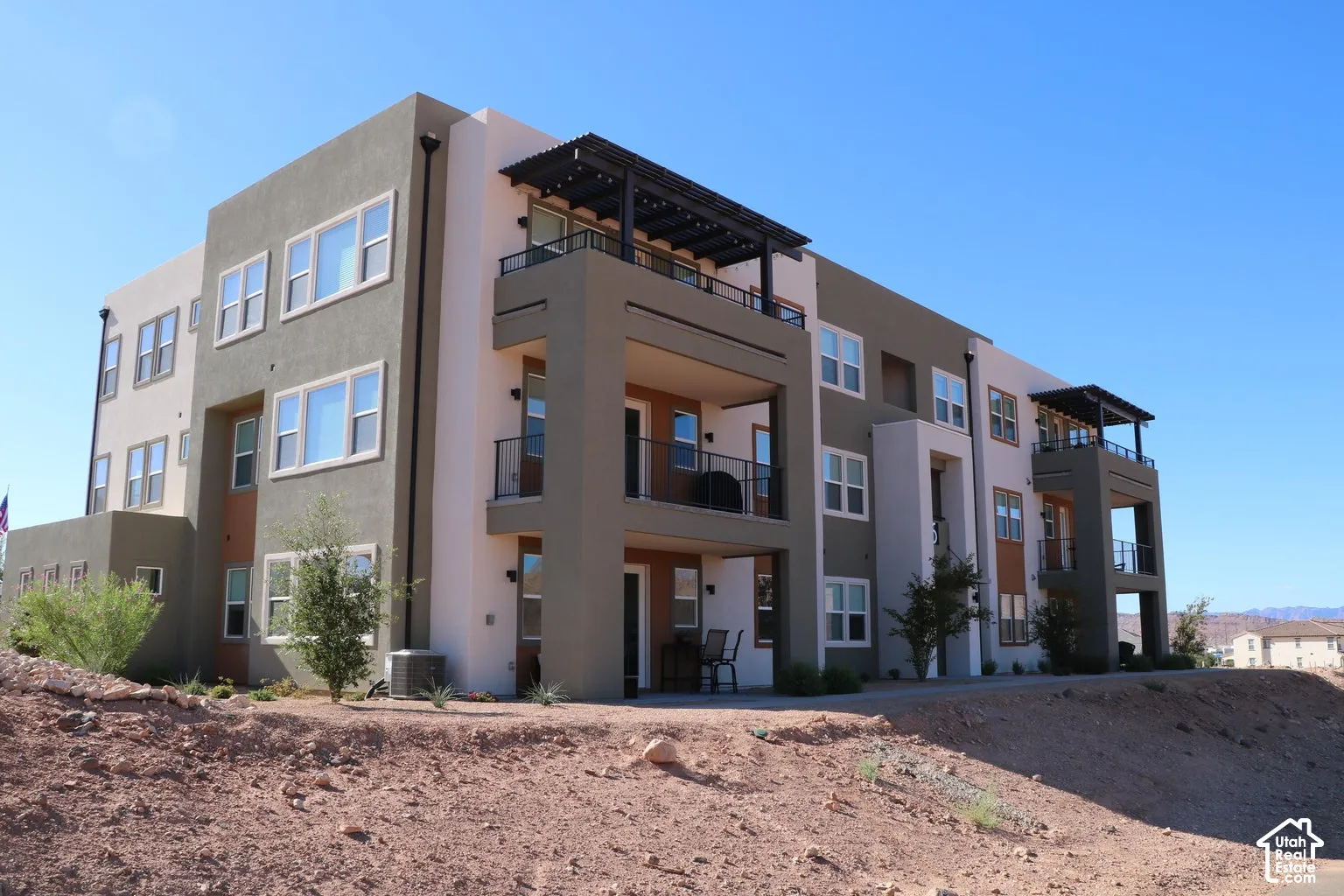Multi-story stucco exterior featuring multiple balconies with metal railings and pergolas