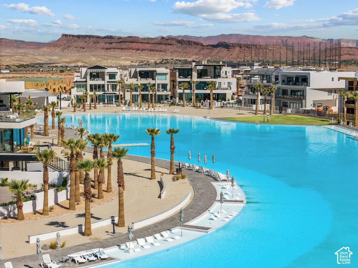 Expansive water feature with sandy shores and surrounding palm trees, complemented by modern residential buildings and distant geological formations