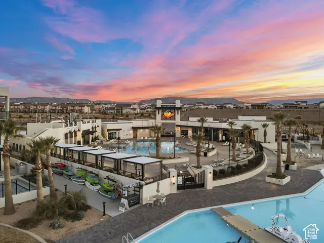 Resort-style community featuring multiple swimming pools, a large building with modern architecture, and extensive hardscaping with palm trees