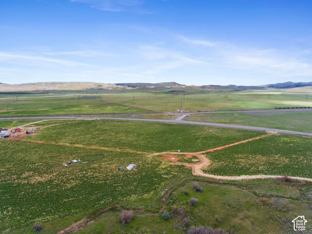 Expansive undeveloped land with a paved road, dirt access paths, and distant mountain backdrops