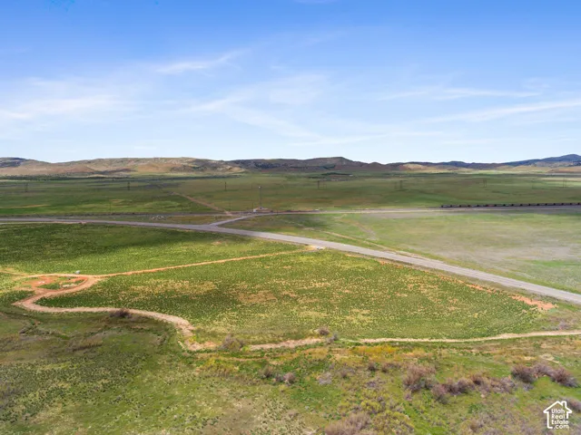Expansive open terrain with a partial paved road and distant mountainous backdrop