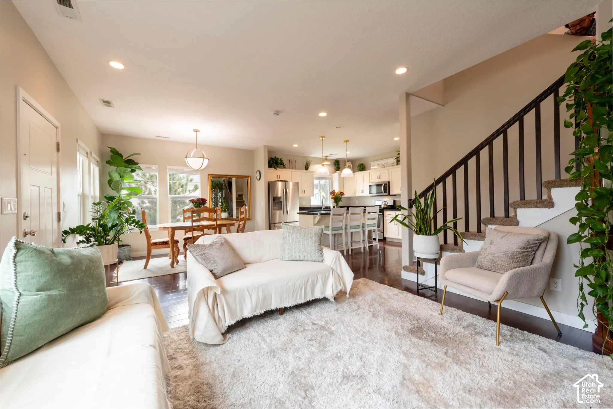 Expansive room with wood-finish flooring, recessed lighting, and a staircase with dark wood-finish balusters