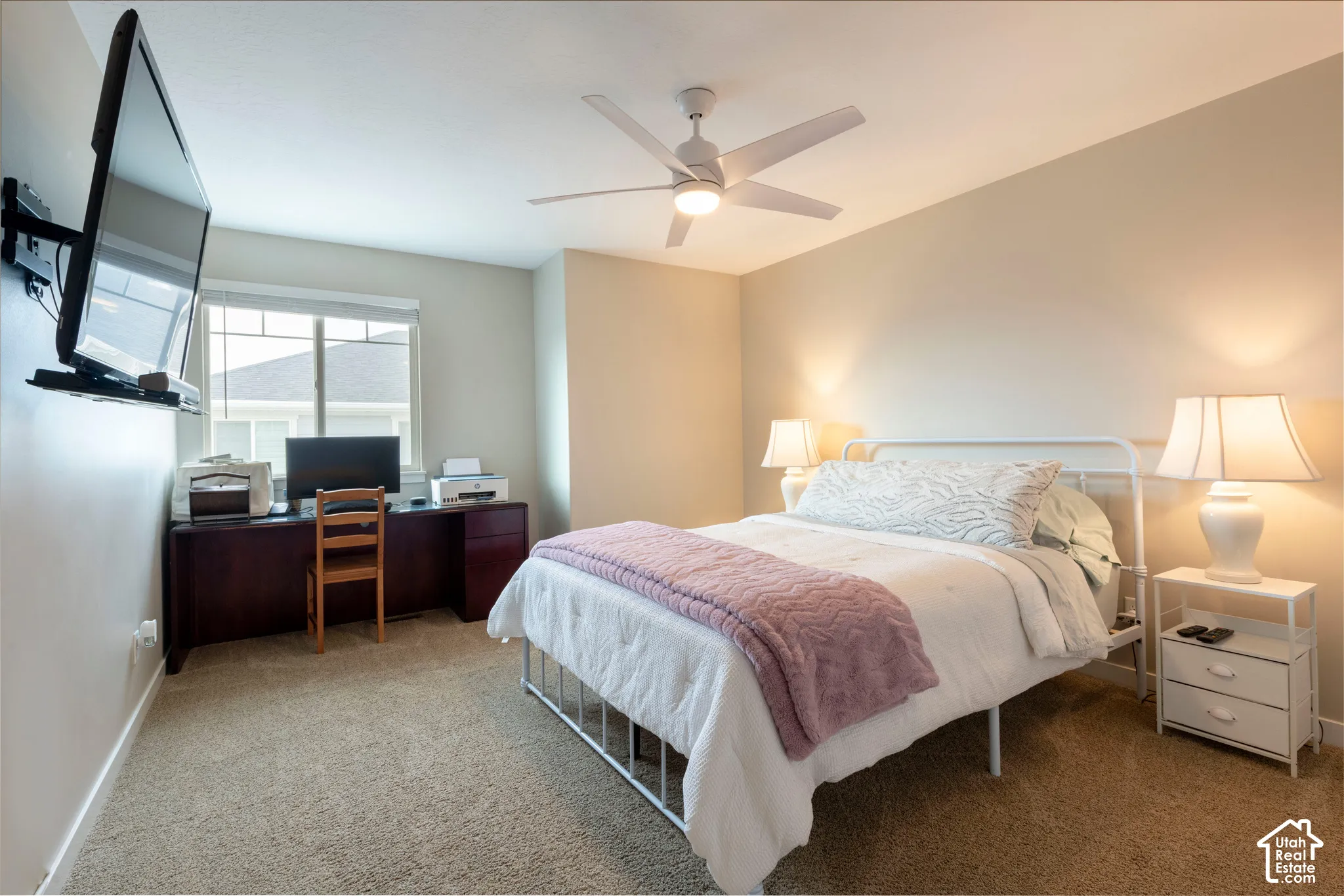 Plush carpeting, a built-in desk, and a ceiling fan with integrated lighting
